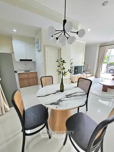 Modern dining area with marble table and stylish chandelier in a bright open-plan living space.