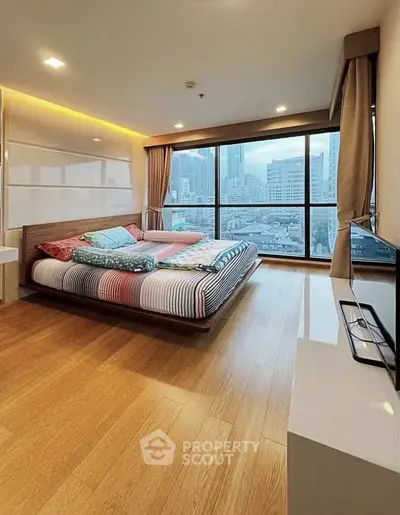 Spacious bedroom with city view, featuring modern decor and large windows for natural light.