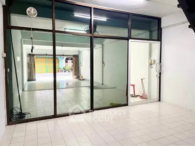 Spacious open-plan room with large glass doors and tiled flooring, ideal for versatile use.