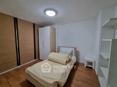 Cozy bedroom with modern furnishings and ample storage space, featuring wooden flooring and soft lighting.
