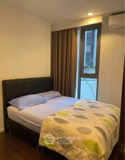 Cozy bedroom with modern decor and large window offering natural light.