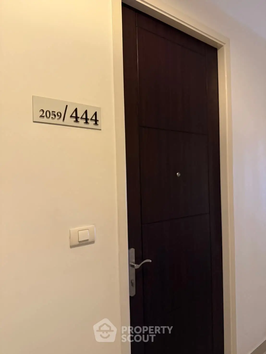 Modern apartment entrance with sleek wooden door and room number 2059/444.