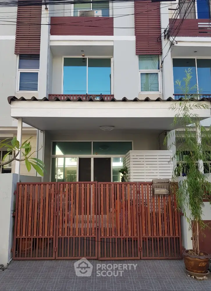 Modern townhouse exterior with wooden gate and balcony in urban setting