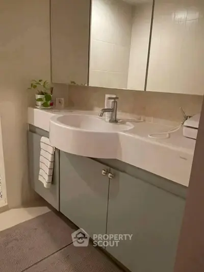 Modern bathroom with sleek vanity and mirror, featuring elegant fixtures and subtle decor.