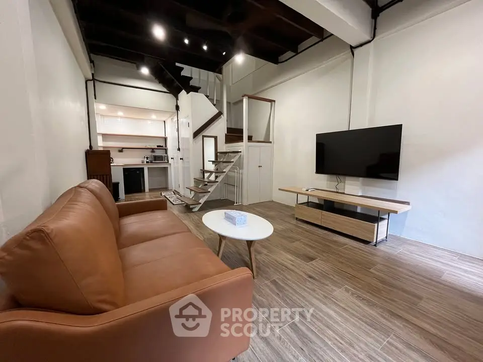 Modern loft-style living room with open kitchen and sleek staircase