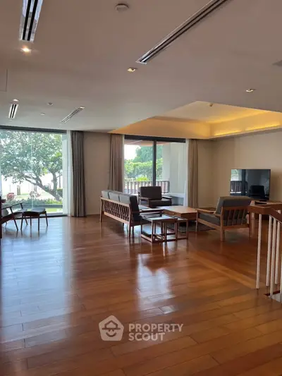 Spacious living room with wooden flooring and large windows offering a scenic view.