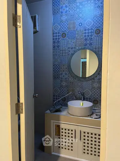 Charming bathroom with stylish patterned tiles and modern round mirror.