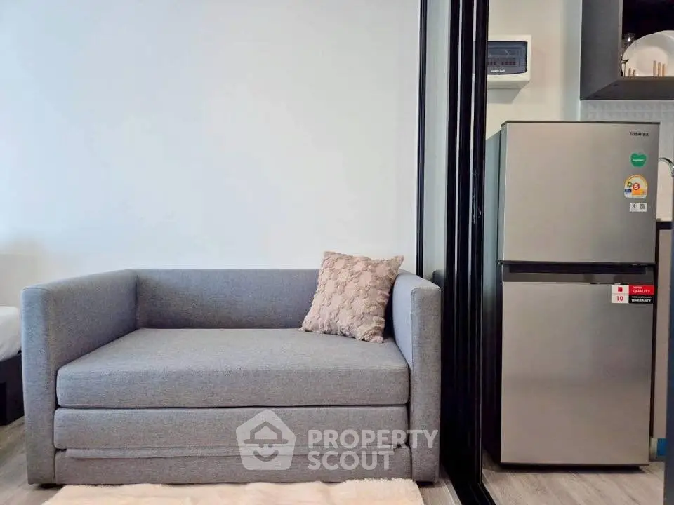 Modern living room with stylish gray sofa and sleek refrigerator, perfect for compact urban living.