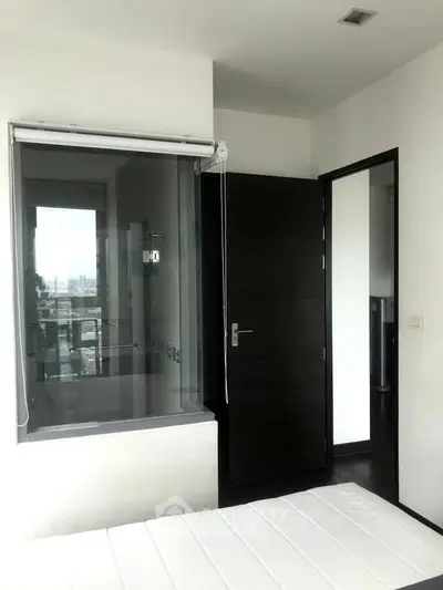 Modern bedroom with large window and city view, featuring sleek design and minimalist decor.