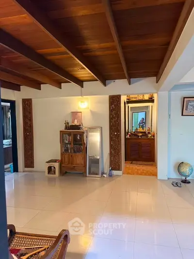 Spacious living area with wooden ceiling and decorative elements, offering a cozy ambiance.