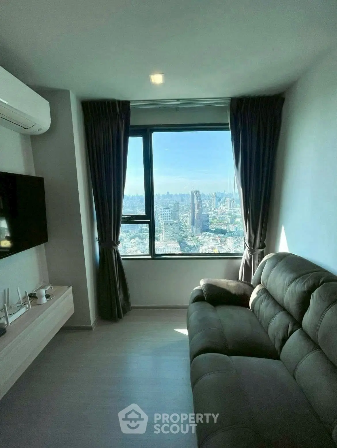 Cozy living room with stunning city view from high-rise apartment window.