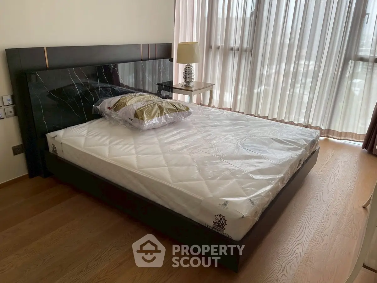 Spacious bedroom with modern bed and large windows offering natural light.