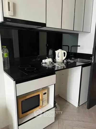 Modern compact kitchen with sleek black and white design, featuring built-in appliances and minimalist style.