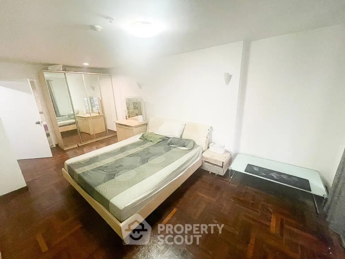 Spacious bedroom with modern decor and parquet flooring