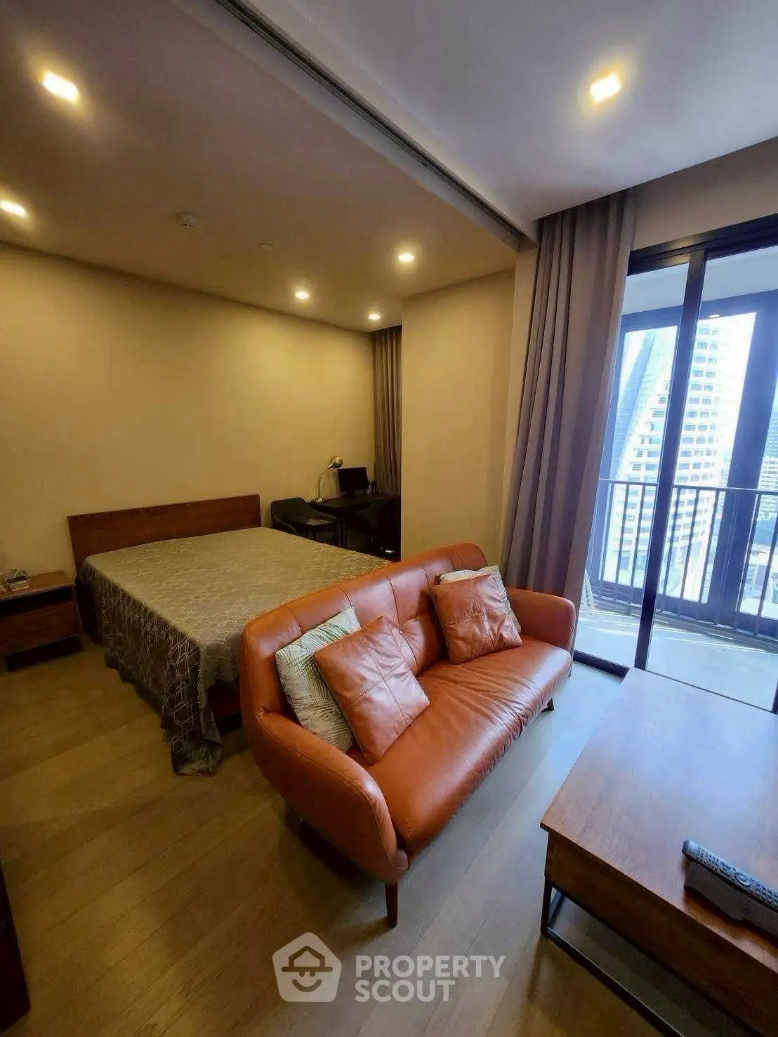 Modern studio apartment with cozy living area and balcony view in urban setting.