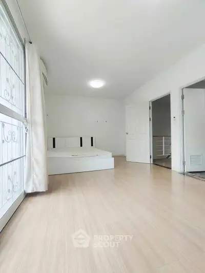 Spacious bedroom with minimalist design and large window for natural light