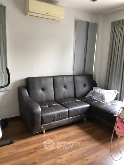 Cozy living room with modern black leather sofa and wooden flooring