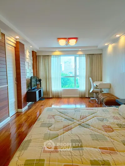 Spacious bedroom with wooden flooring and large window offering city view
