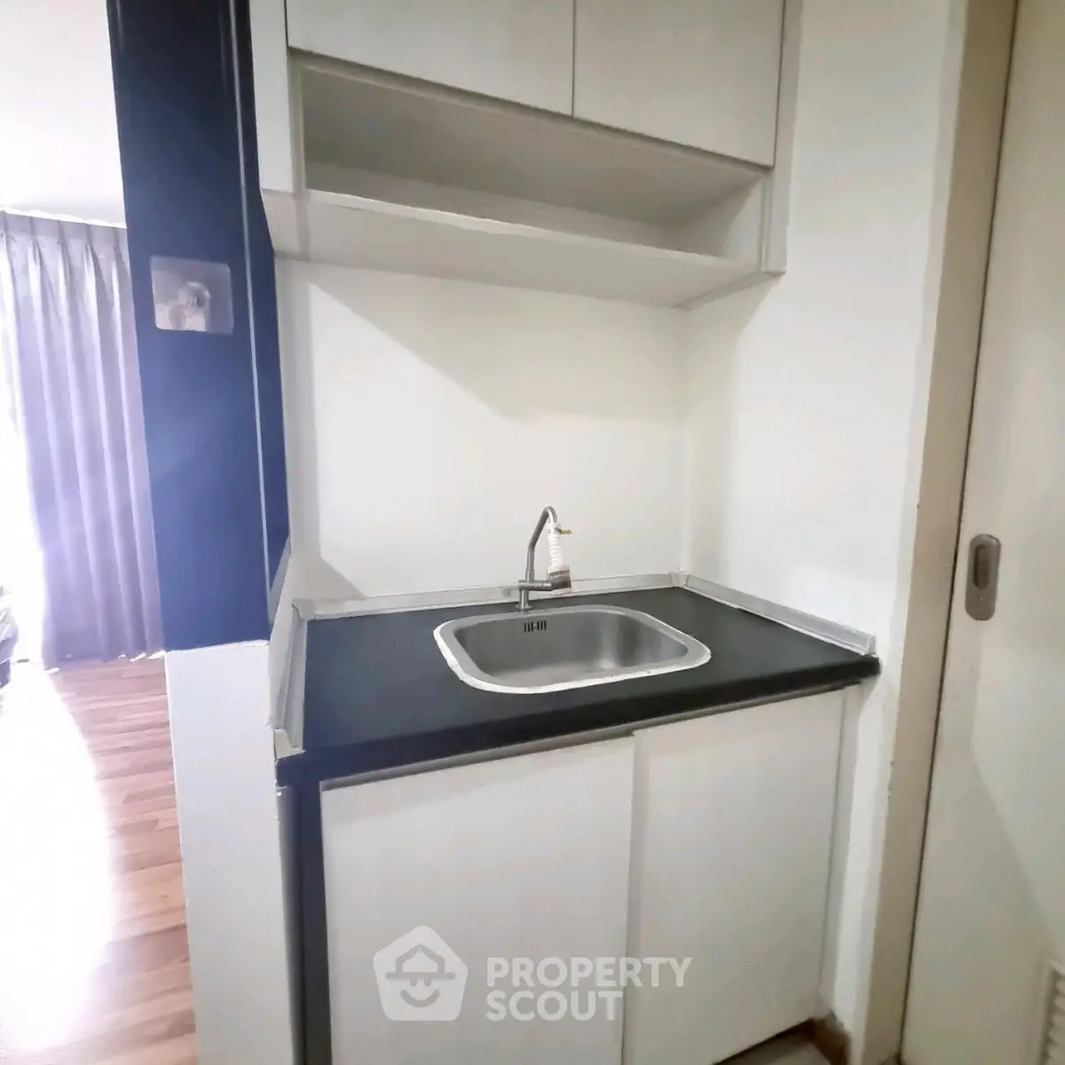 Compact kitchen area with sleek cabinetry and modern sink in cozy apartment.