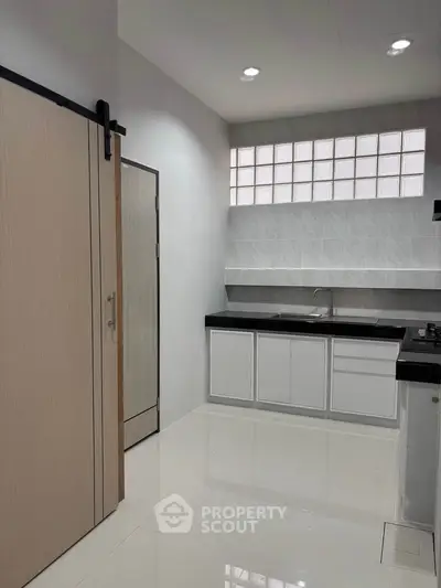 Modern minimalist kitchen with sleek white cabinets and black countertops