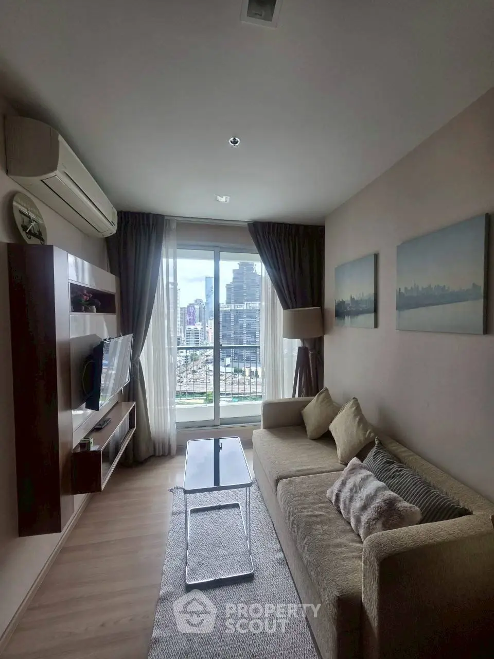 Modern living room with city view, featuring cozy sofa and wall-mounted TV, perfect for urban living.
