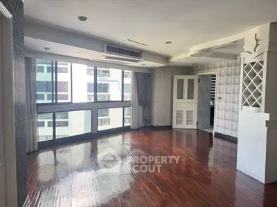 Spacious living room with hardwood floors and large windows in modern apartment