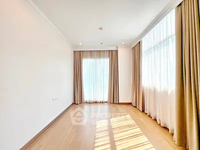 Spacious sunlit room with large windows and elegant curtains, perfect for a modern living space.