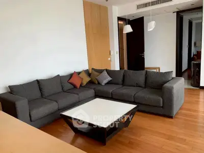 Spacious modern living room with stylish gray sectional sofa and wooden flooring.