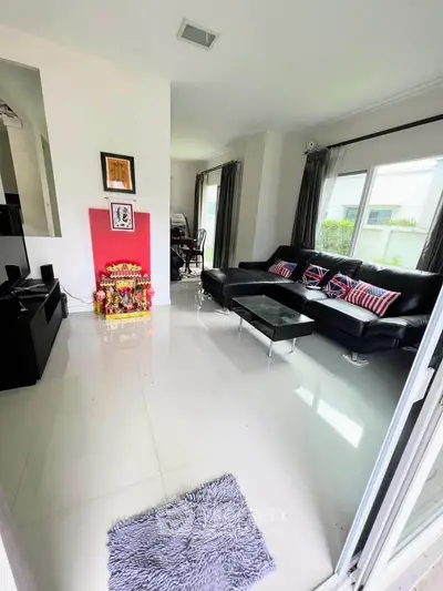 Spacious modern living room with sleek black sofa and large windows for natural light.