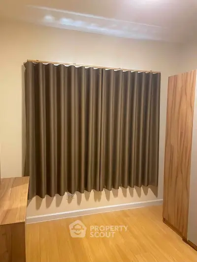 Cozy bedroom with wooden furniture and elegant curtains, perfect for a serene living experience.