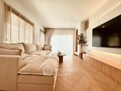 Luxurious modern living room with plush sofa and large TV, featuring elegant decor and natural light.