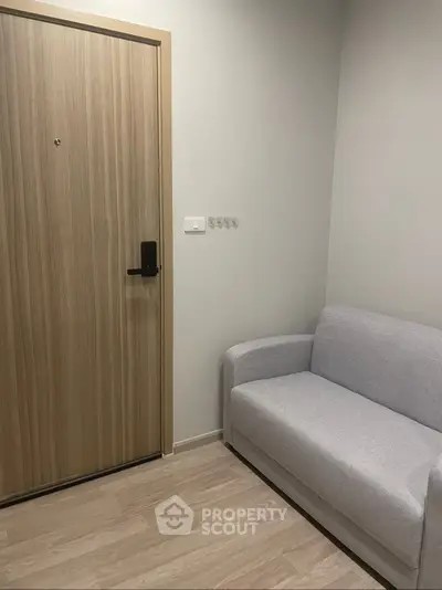 Cozy small living room with a modern sofa and wooden door, perfect for compact spaces.