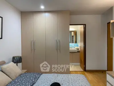 Modern bedroom with built-in wardrobe and view into stylish bathroom