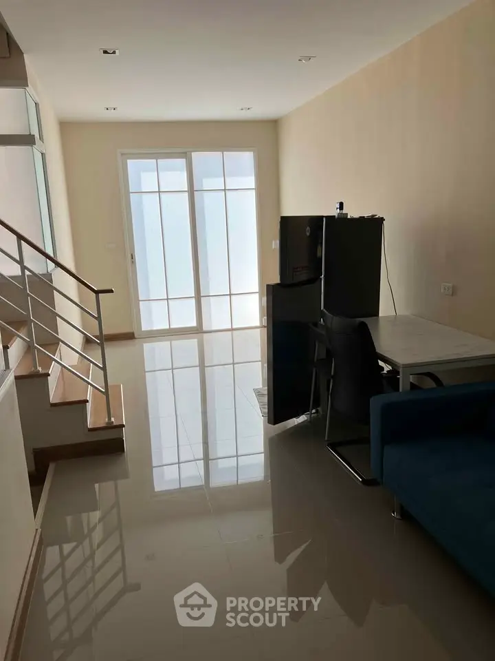 Modern living room with sleek staircase and natural light, perfect for contemporary living.