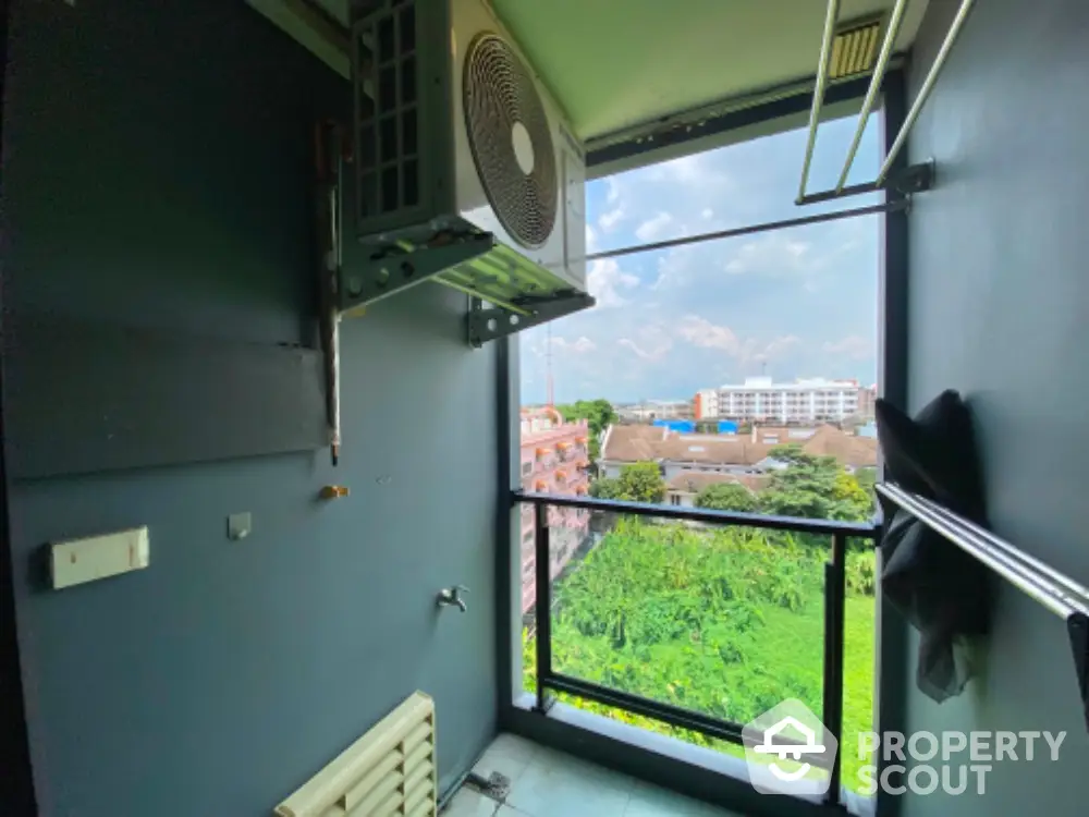 Modern balcony with air conditioning unit and scenic view of greenery and buildings.