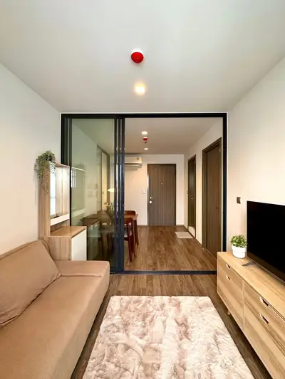 Modern living room with stylish decor and open layout, featuring a cozy sofa and sleek wooden furniture.