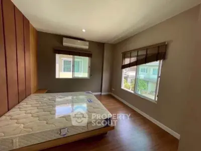 Spacious bedroom with large windows and wooden flooring in modern home.