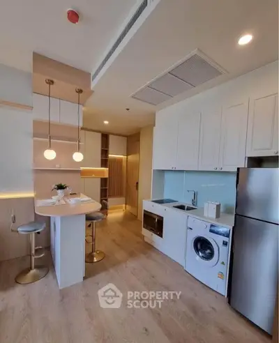 Modern kitchen with open layout, featuring sleek appliances and stylish lighting, perfect for contemporary living.