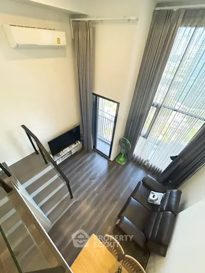 Modern loft-style living room with high ceilings and large windows offering a stunning view.