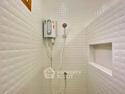 Modern bathroom shower area with white textured tiles and built-in shelf.