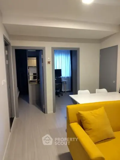 Modern living room with vibrant yellow sofa and sleek dining area, perfect for urban living.