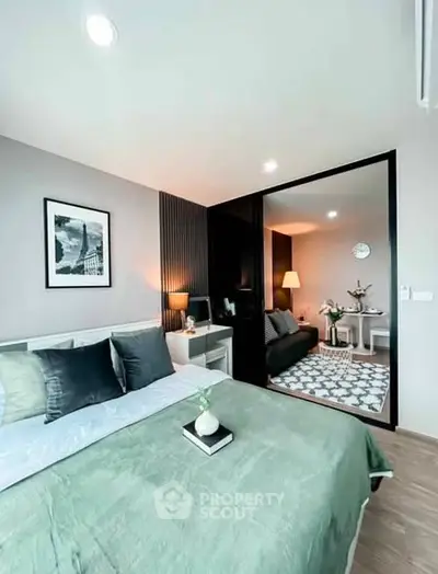 Modern bedroom with stylish decor and adjacent living area in open layout apartment.