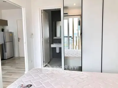 Modern bedroom with mirrored closet and view of kitchen and balcony