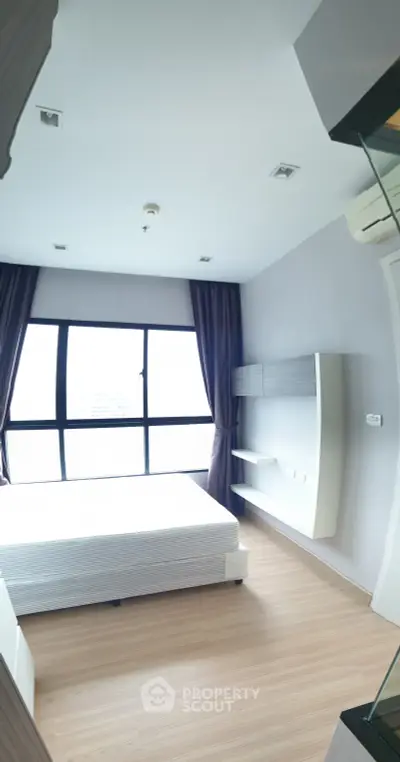 Bright and modern bedroom with large window and minimalist design in a high-rise apartment.