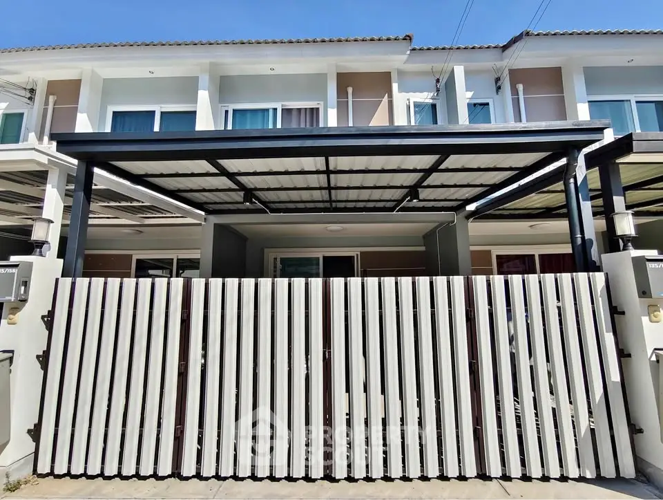Modern townhouse exterior with gated entrance and covered parking area.