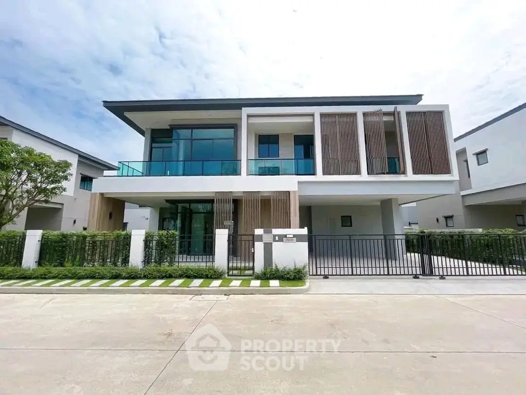 Modern two-story house with large windows and sleek design in a suburban neighborhood.