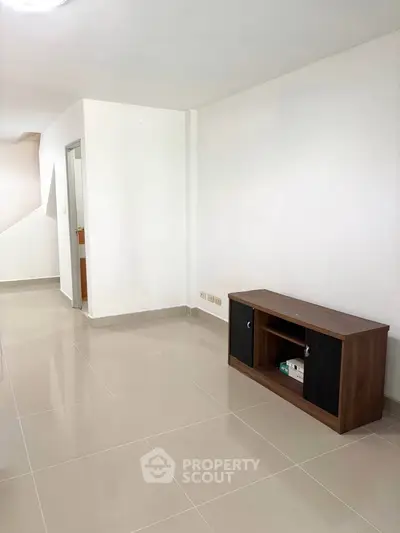 Spacious modern living area with sleek tile flooring and minimalist furniture.