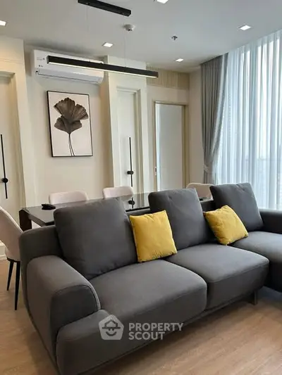 Modern living room with stylish gray sofa and elegant dining area