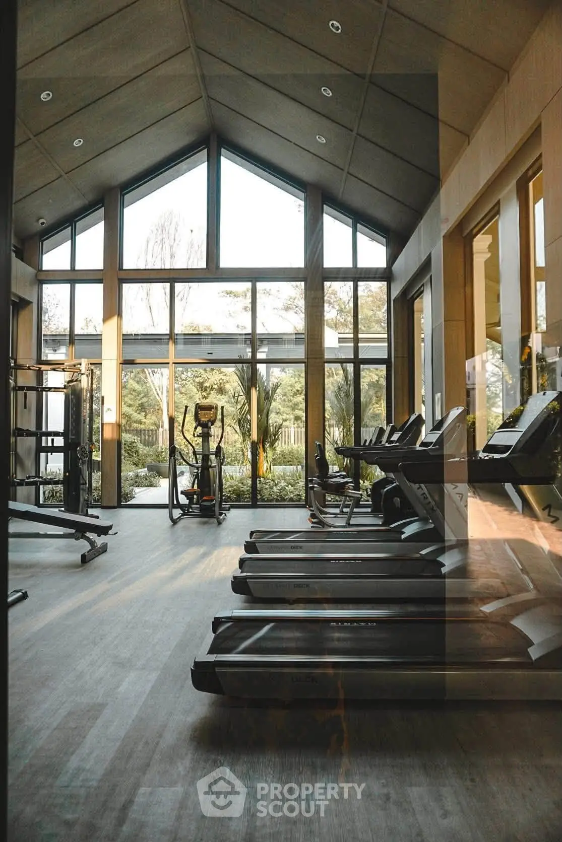 Luxurious gym with modern equipment and large windows offering scenic views, perfect for fitness enthusiasts.