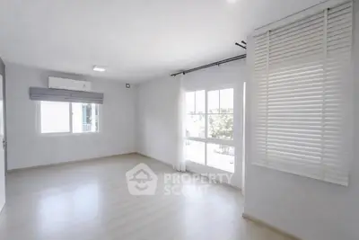 Spacious and bright empty room with large windows and modern blinds.
